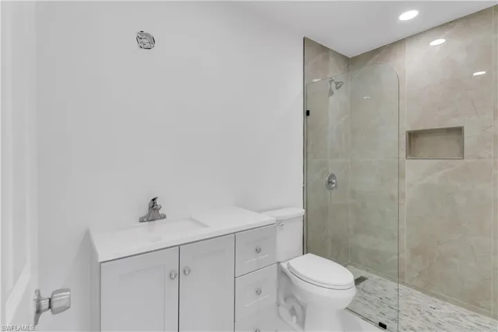 Bathroom with a tile shower, toilet, and vanity