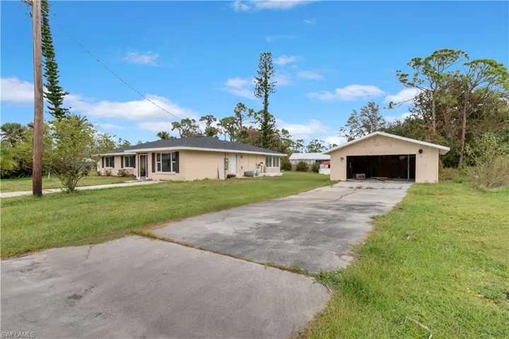 Ranch-style home with a front yard, an outbuilding, and a garage