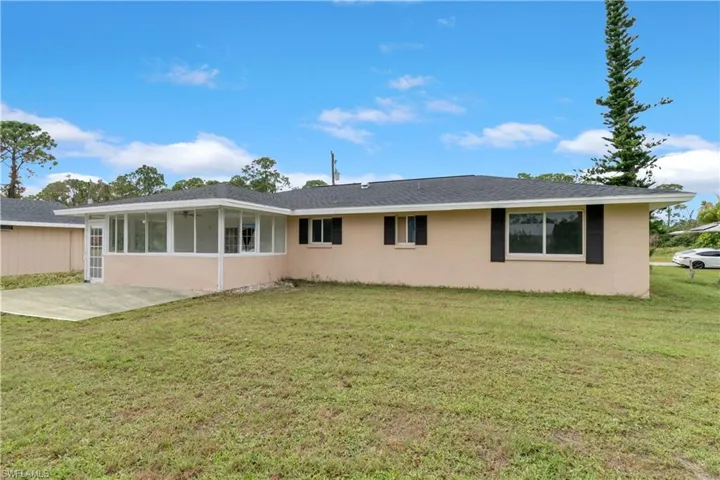 Rear view of property with a yard, a patio area, and a sunroom