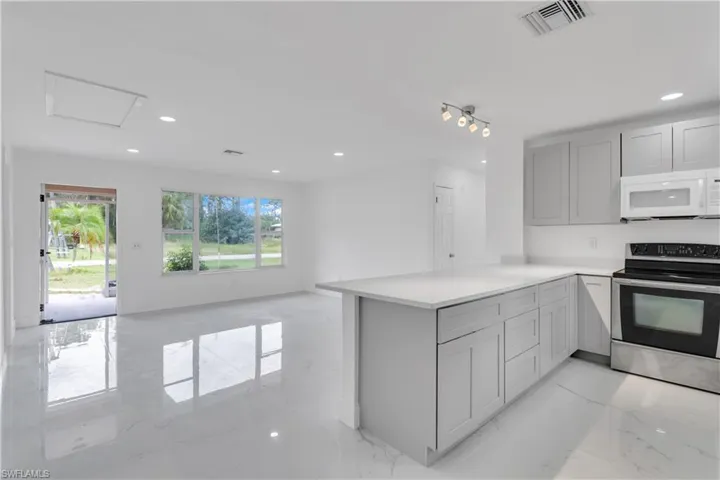 Kitchen featuring stainless steel electric stove, kitchen peninsula, and gray cabinetry