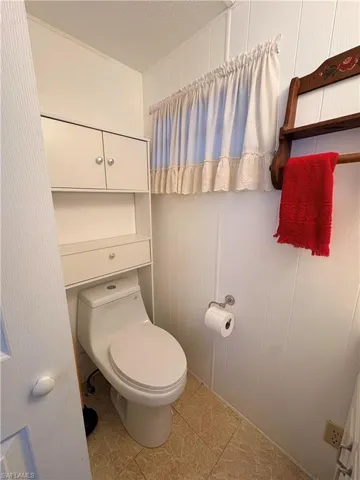 Bathroom with a decorative wall, a textured ceiling, light tile patterned flooring, and wood walls
