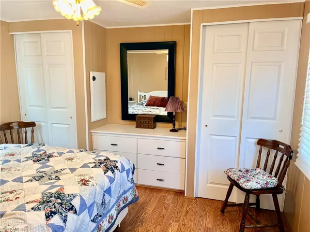 Bedroom featuring multiple closets, light wood finished floors, a ceiling fan, and ornamental molding