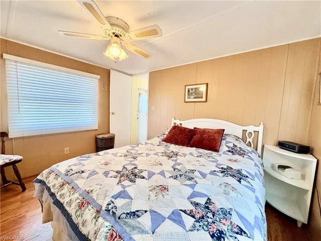 Bedroom featuring wood finished floors, wooden walls, and ceiling fan