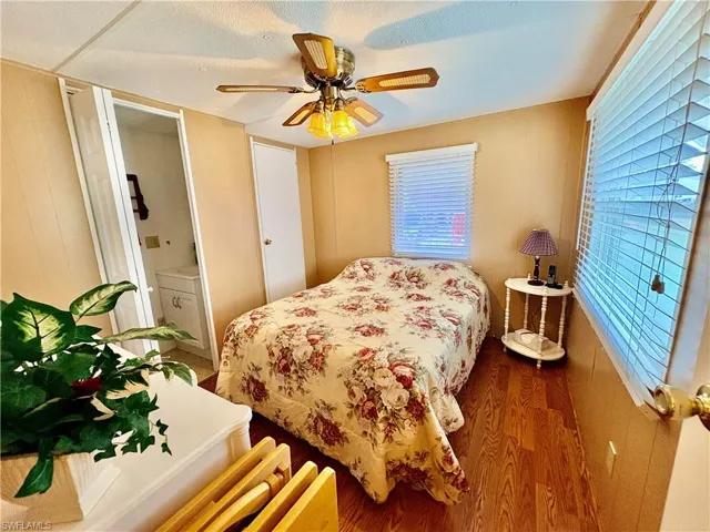 Bedroom featuring wood finished floors, a ceiling fan, ensuite bathroom, and wood walls