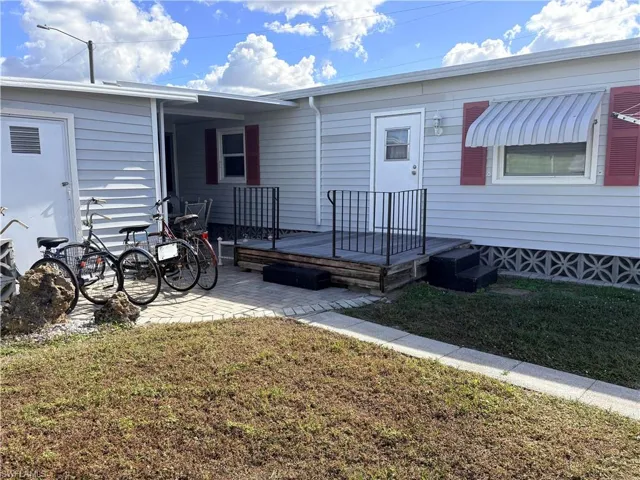 View of exterior entry featuring a yard and a wooden deck