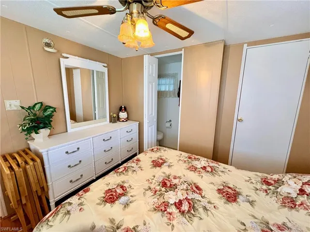Bedroom with a ceiling fan, a decorative wall, and ensuite bath