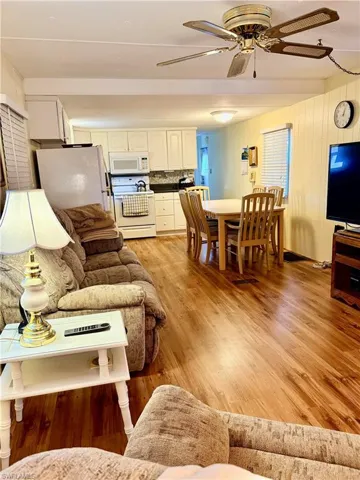 Living area featuring light wood-type flooring, ceiling fan, and wood walls