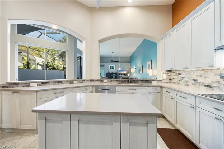 Kitchen with lovely views of private pool, open airspace and tropical foliage, custom backsplash, Bosch appliances, a center island, light wood designer cabinets, light quartz composite countertops, and  electric cooktop make this any home chef's private oasis