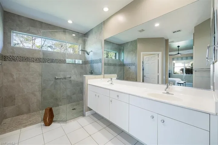 Master bathroom ensuite with dual sinks, glass shower enclosure, neutral tile and ample sunlight