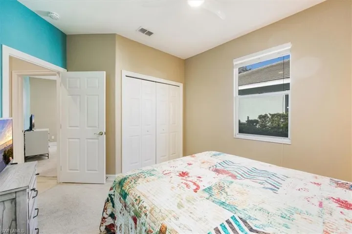 Guest bedroom with light colored carpet and ceiling fan with lovely accent walls