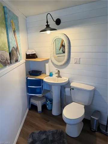 Bathroom featuring dark wood finished floors and wooden walls