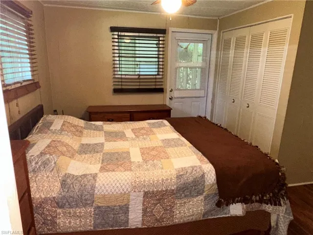 Bedroom featuring ornamental molding, a closet, a ceiling fan, and wood finished floors