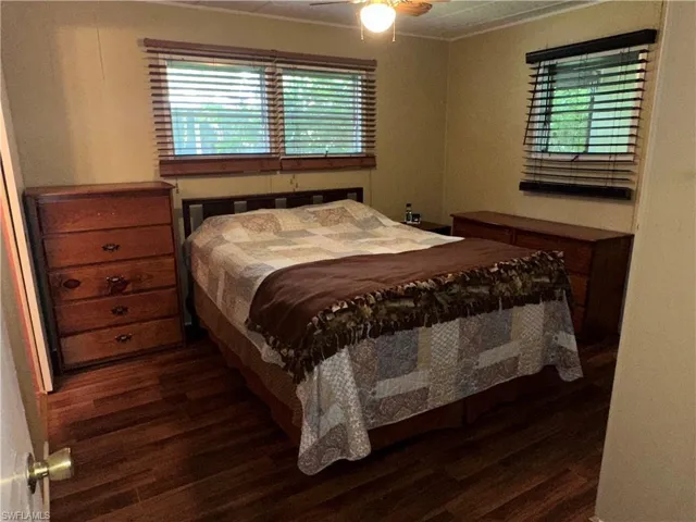 Bedroom with dark wood finished floors, a ceiling fan, and crown molding