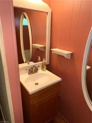 Half bath featuring vanity and wood walls