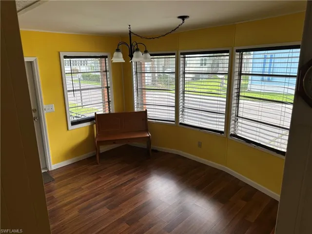 Living area with dark wood finished floors, a chandelier, and ornamental molding