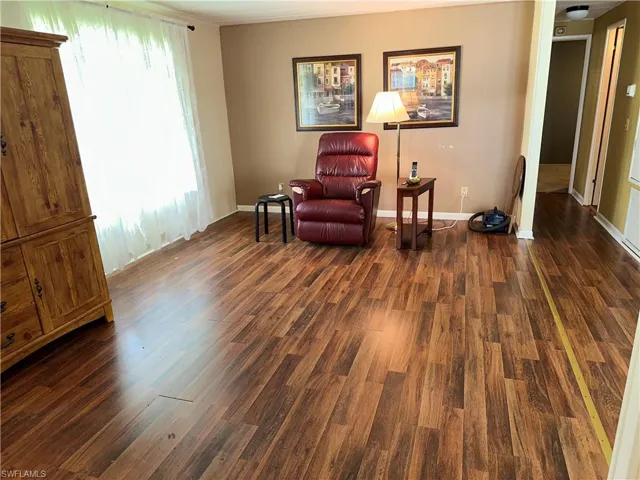 Sitting room with dark wood-style flooring and baseboards