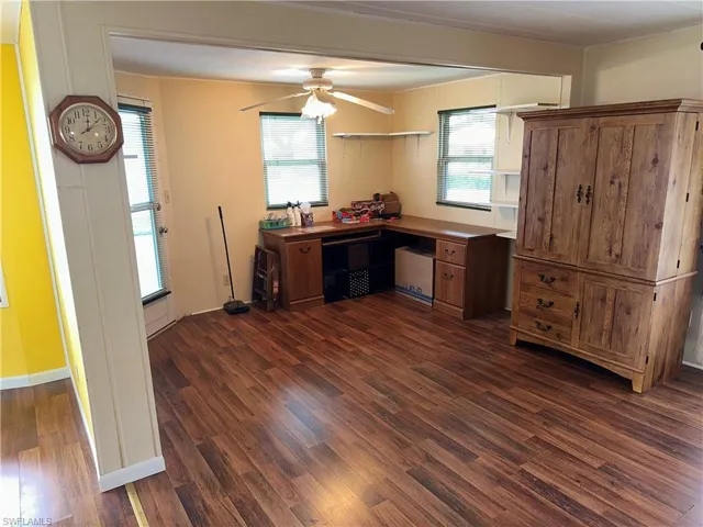 Office space with dark wood-style flooring and a ceiling fan
