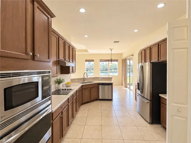 Kitchen featuring stainless steel appliances, wood cabinetry, light-toned countertops, and tile flooring