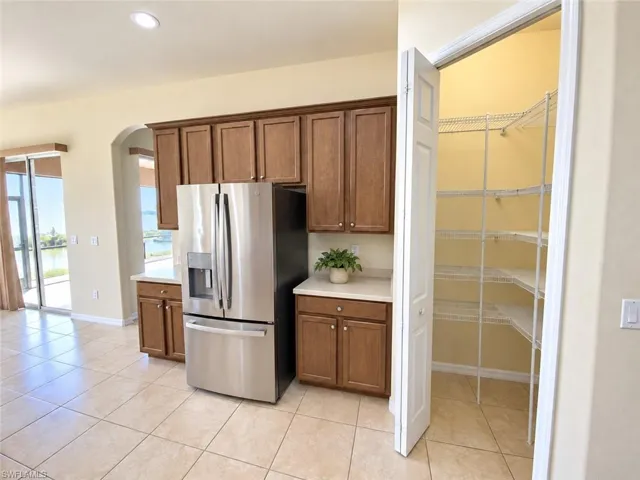 Kitchen featuring wood cabinetry, light-colored countertops, and a stainless steel refrigerator