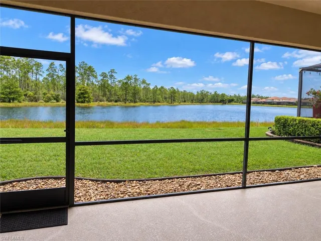 Screened lanai with concrete flooring, overlooking a body of water, manicured lawn, and mature trees