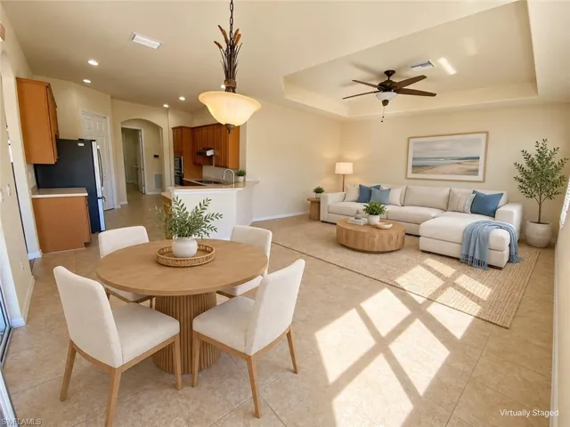 Spacious open-concept living area featuring a tray ceiling, recessed lighting, and tile flooring