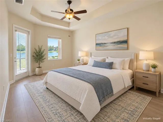 Tray ceiling with a ceiling fan light fixture, wood-finish flooring, and a glass door with blinds leading to a balcony