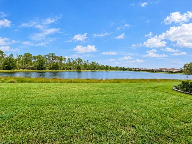 Expansive green space with a manicured lawn, bordered by a tranquil lake