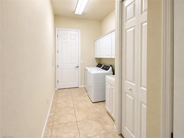 Tile flooring, white shaker-style cabinetry, white paneled doors, and a built-in utility sink