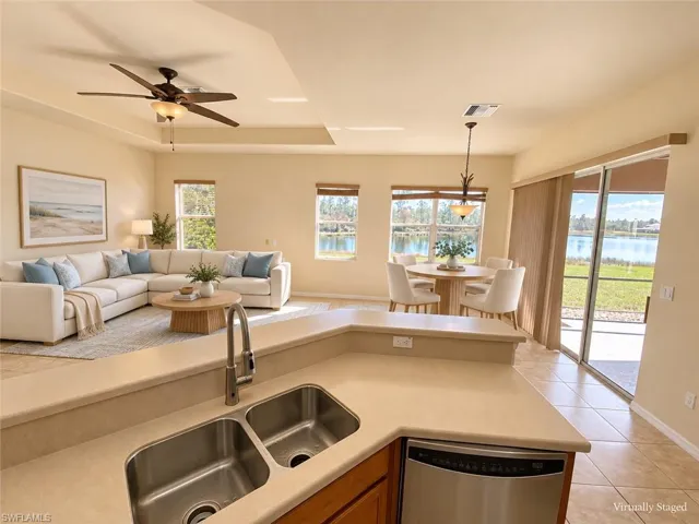 Open-concept living space featuring a ceiling fan, dual basin stainless steel sink, stainless steel dishwasher, and sliding glass doors opening to the patio