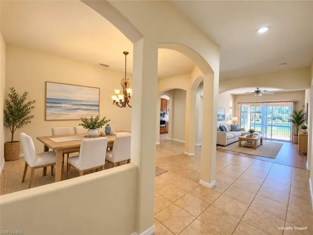 Archways and tile flooring define the entry leading to a living area with wood-finish flooring and sliding glass doors