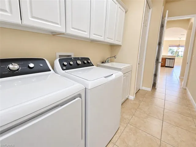 Laundry area featuring upper cabinetry, a utility sink, and tile flooring