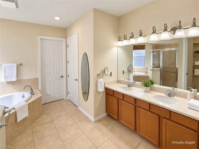 Dual vanity with light-toned countertop, wood-finish cabinetry, and brushed nickel hardware