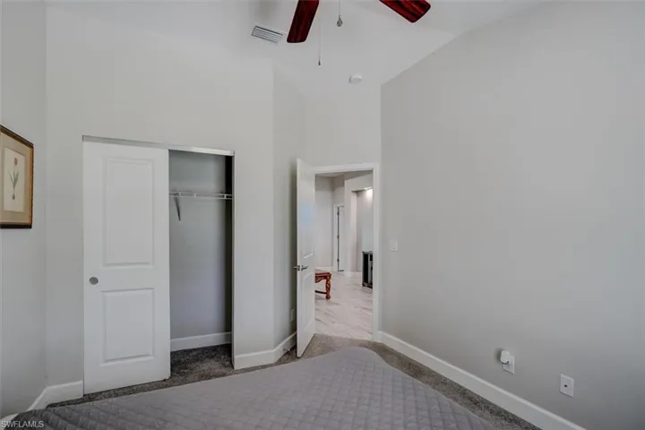 Unfurnished bedroom with carpet, a closet, lofted ceiling, and ceiling fan