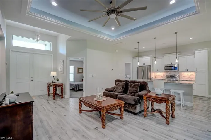 Living room featuring light hardwood / wood-style floors, a tray ceiling, and ceiling fan
