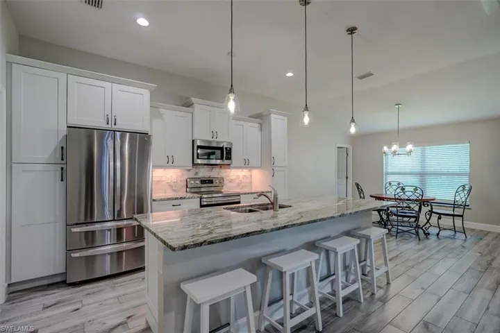 Kitchen with white cabinetry, a center island with sink, appliances with stainless steel finishes, and sink