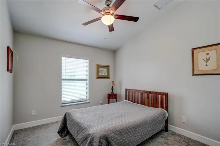Bedroom with ceiling fan, light colored carpet, and lofted ceiling