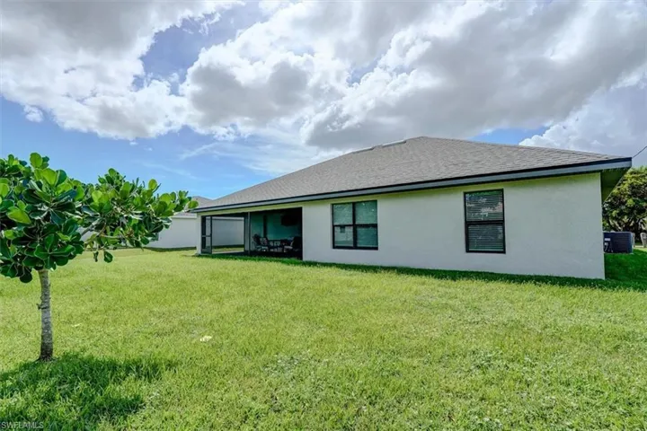 Back of property featuring a lawn and cooling unit