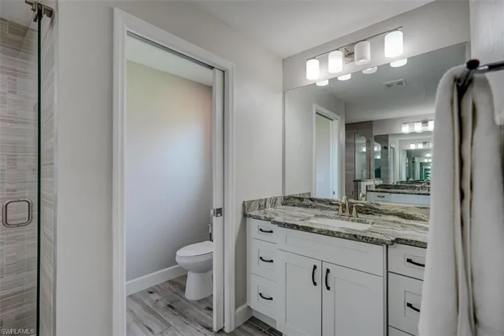 Bathroom with wood-type flooring, vanity, toilet, and an enclosed shower
