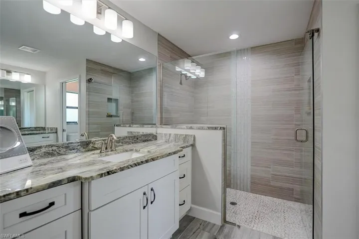 Bathroom featuring a shower with door, vanity, and hardwood / wood-style flooring
