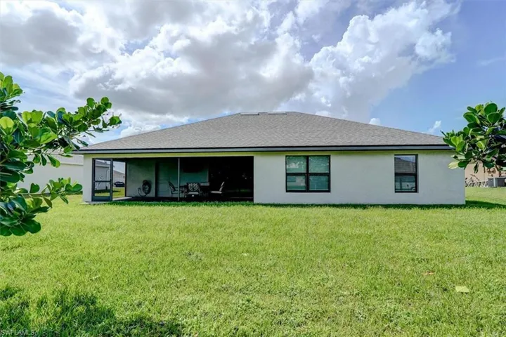 Back of house featuring a lawn and cooling unit