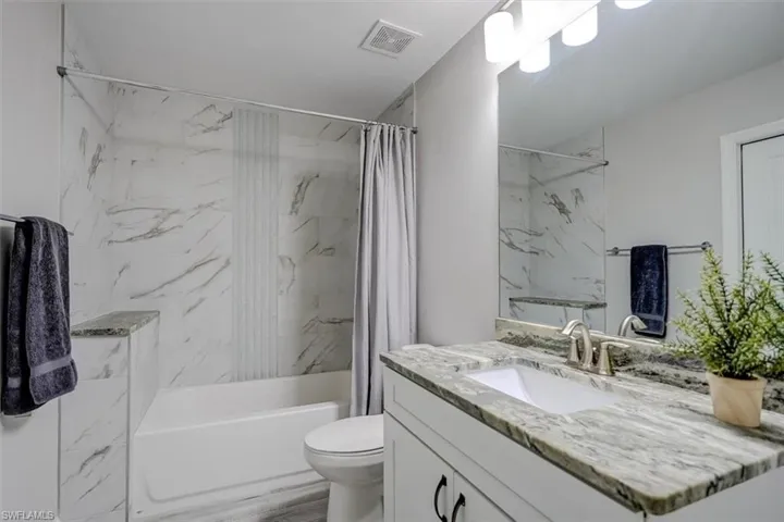 Full bathroom featuring shower / bath combo with shower curtain, vanity, and toilet