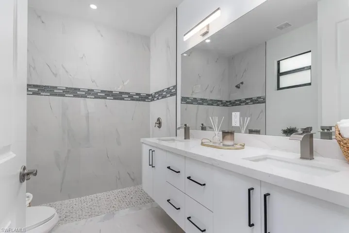 Bathroom featuring toilet, tiled shower, and vanity