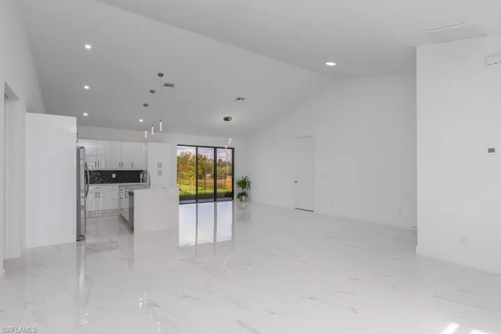 Unfurnished living room featuring lofted ceiling and sink