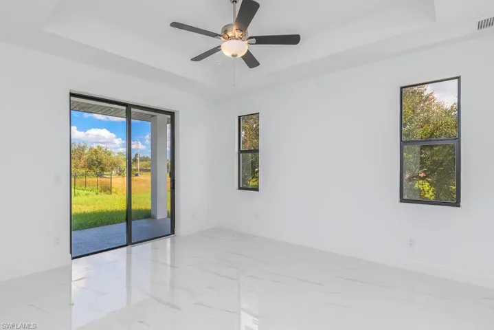 Spare room with ceiling fan, a wealth of natural light, and a raised ceiling