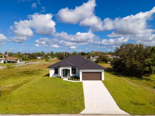 View of front facade featuring a garage and a front lawn
