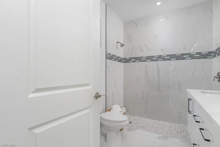 Bathroom featuring vanity, toilet, and tiled shower