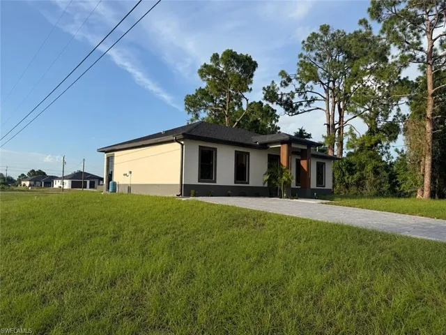 Contemporary single-story residence featuring a stucco exterior with a dark gray base and light beige upper facade