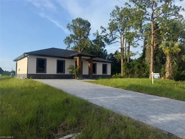 Contemporary exterior with a dark shingle roof, light stucco siding, and dark trim