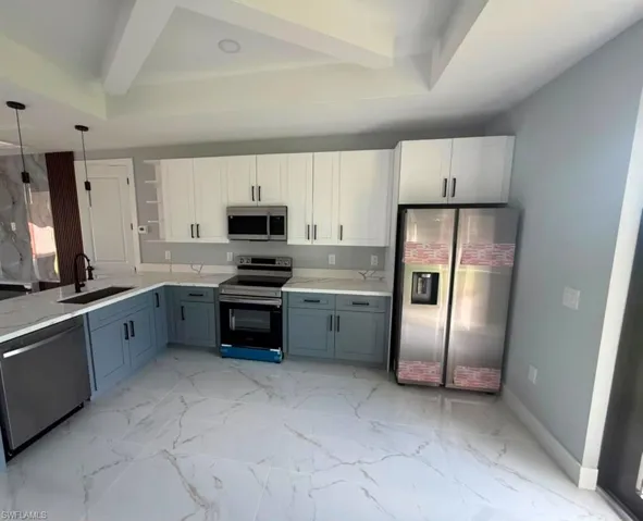 Modern kitchen featuring two-tone cabinetry with white upper cabinets and gray lower cabinets, complemented by a stainless steel appliance suite
