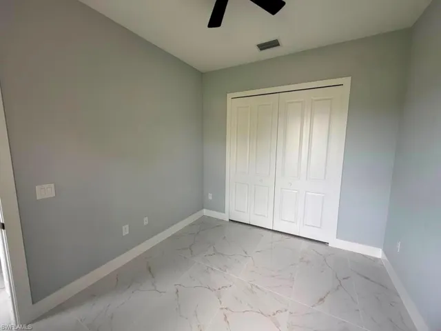 Room featuring large format tile flooring, light gray wall paint, and white baseboards